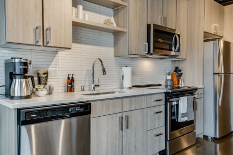 Modern kitchen featuring light wood cabinets, a black stove, and a coffee maker.