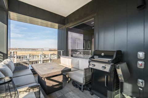 A cozy balcony featuring a grill and sleek seating with a city view.