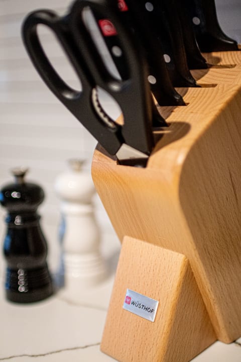 A wooden knife block from Wüsthof containing various knives and scissors, with salt and pepper shakers in the background.