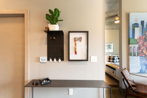 Modern entryway with a wall shelf, framed axe art, potted plant, and decorative items.