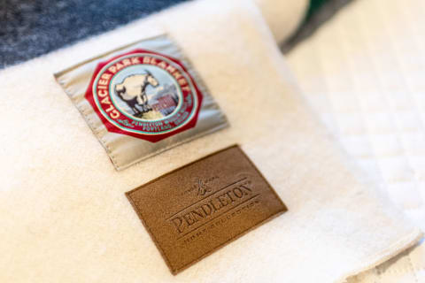 Diverse patches on a Pendleton blanket featuring Glacier Park design and leather logo.