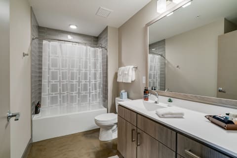 Modern bathroom with a bathtub, vanity, and geometric-patterned shower curtain.