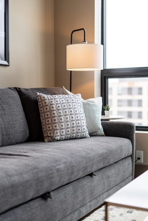 A modern living room featuring a gray sofa with pillows and a side table.