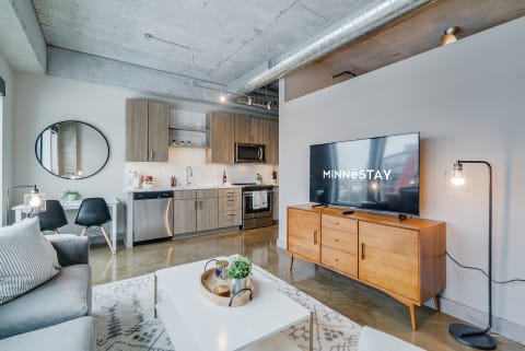 Modern living room with kitchen, featuring stylish furnishings and decor.