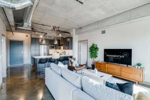 Open-concept living room and kitchen in a modern apartment featuring industrial design elements.