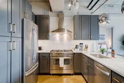 Contemporary kitchen featuring gray cabinets, stainless steel appliances, and a marble countertop.