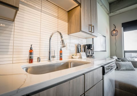 Modern kitchen with marble countertop, high-arc faucet, and coffee maker.