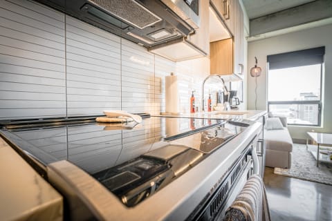 Modern kitchen with a glass stovetop and light gray tile backsplash.