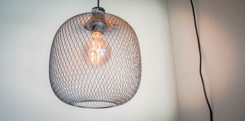Modern pendant light with a wire mesh shade and a glowing vintage bulb.