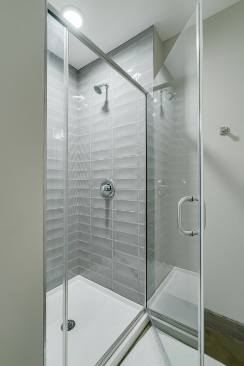 Contemporary shower with glass walls and gray tiled interior.