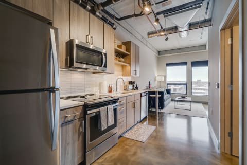 Modern kitchen with stainless steel appliances and a cozy living area in a contemporary apartment.