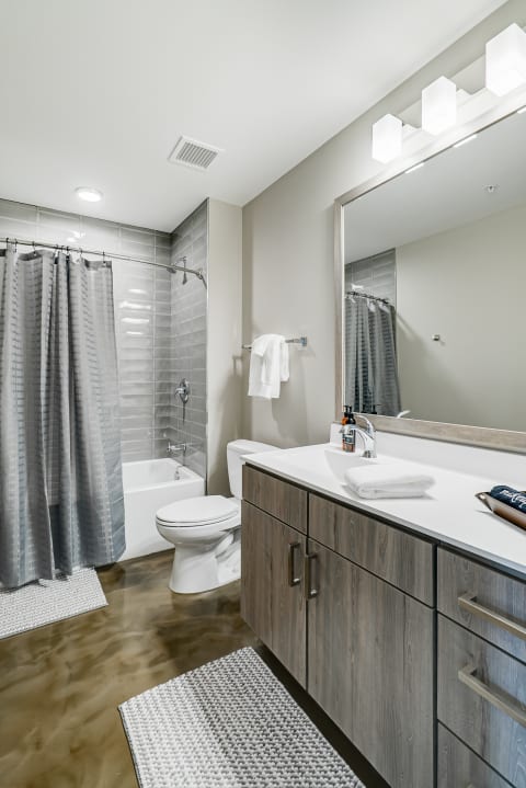 Modern bathroom with gray tiles, white fixtures, and wooden cabinetry.