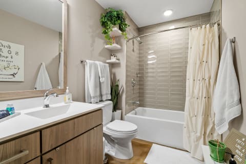 Modern bathroom with a white vanity, beige walls, and a bathtub with a shower.