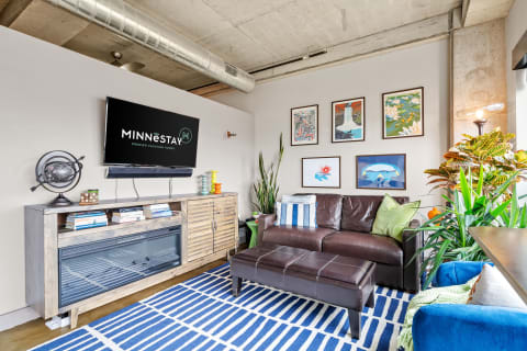 A cozy living room with a leather sofa, modern decor, and colorful artworks.