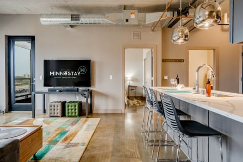 Interior of a contemporary vacation rental with a living area, kitchen bar, and large windows.