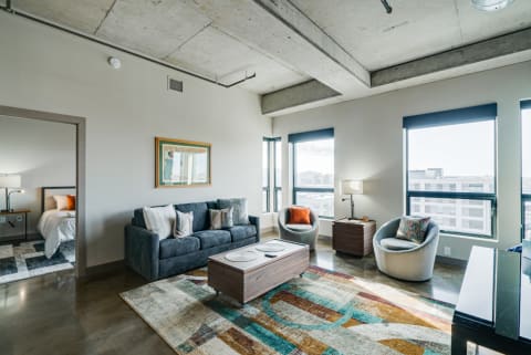 Stylish living room featuring a grey sofa, colorful rug, and large windows.