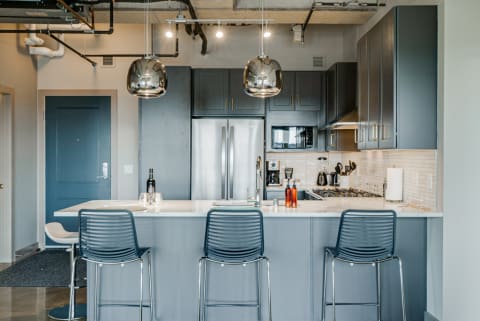 Modern kitchen with marble countertop, dark cabinetry, and stylish pendant lights.