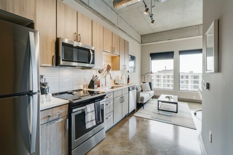 Interior view of a modern kitchen and living space featuring stainless steel appliances and a light gray sofa.