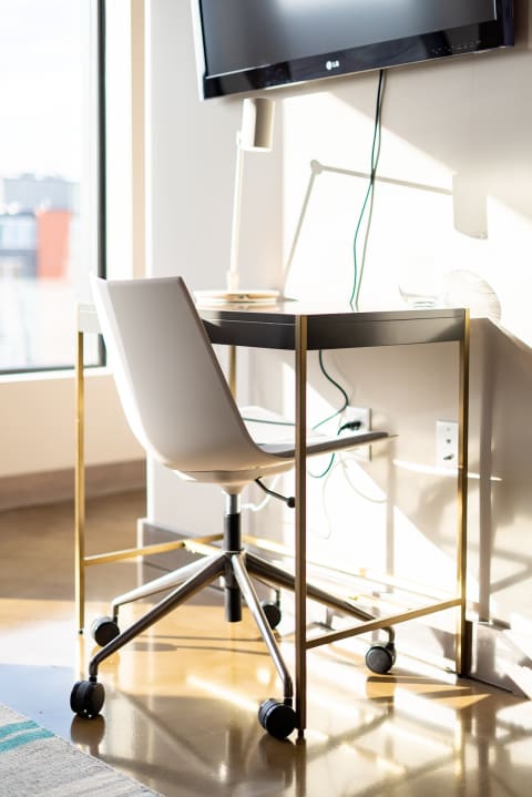 Minimalist workspace featuring a modern desk and white chair, illuminated by sunlight.