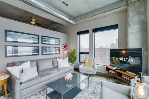 Modern living room with a gray sofa, armchair, and urban landscape photographs.