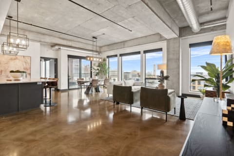 Open-concept living space with concrete ceilings and large windows overlooking the city.