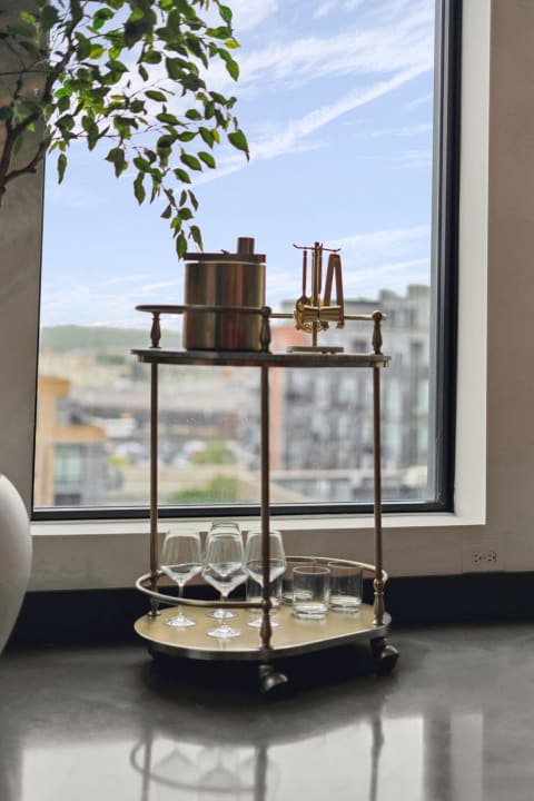 Modern bar cart near a window with an ice bucket and glassware.