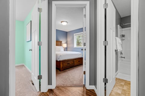 View of a hallway leading to a peaceful bedroom with blue walls and a wooden bed frame.