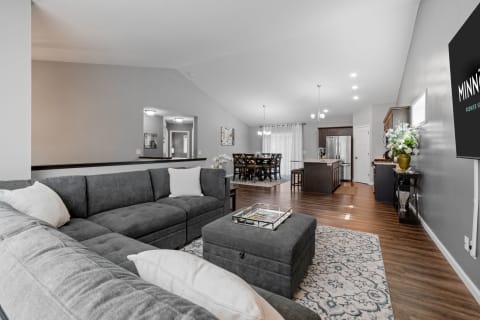 Interior view of a modern living room with a sectional sofa, dining area, and kitchen.