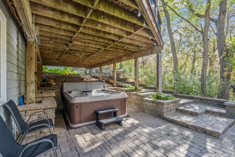 A hot tub under a wooden deck in a landscaped outdoor space.