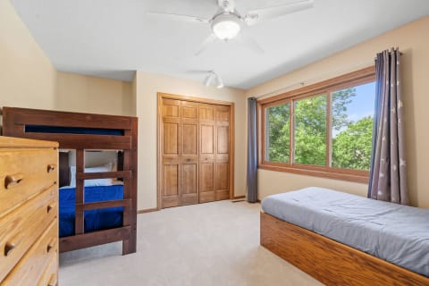 A bright and inviting bedroom with a bunk bed and a single bed, natural light from the window.