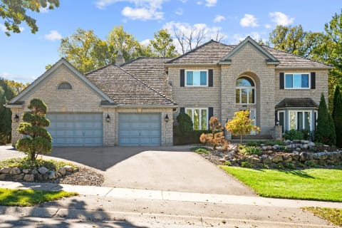 Front view of a two-story house with brick exterior and landscaped yard.