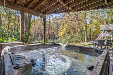 Hot tub beneath a gazebo, surrounded by trees with autumn leaves, and outdoor seating area.