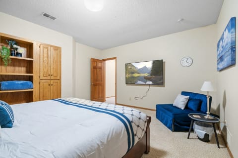 A well-decorated bedroom featuring a bed, a TV, and comfortable seating.