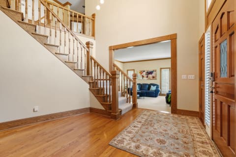 Entrance of a home with a staircase, area rug, and visible living room.