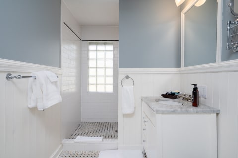 Modern bathroom with blue walls, white tiles, and a marble countertop.