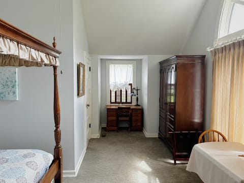 A bright and elegant bedroom with a four-poster bed and vintage wooden furniture.