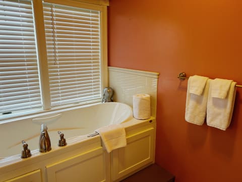 Luxurious bathroom with a soaking tub and white towels against orange walls.
