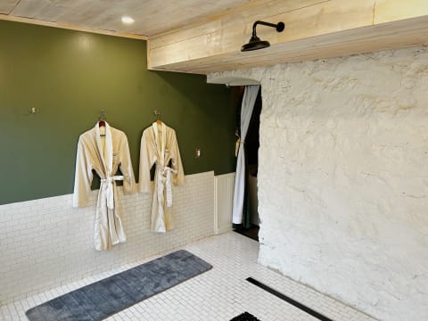 Luxurious spa setting with beige robes hanging on a green wall and a textured stone wall.