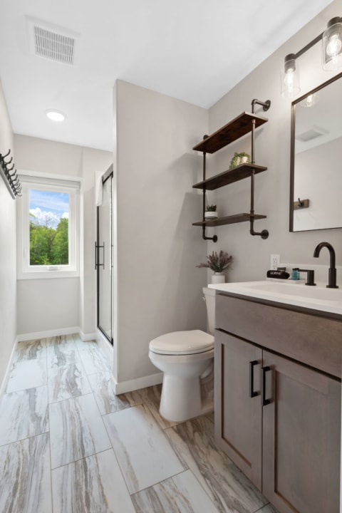 Modern bathroom with a neutral color palette, floating shelves, and a view of greenery.