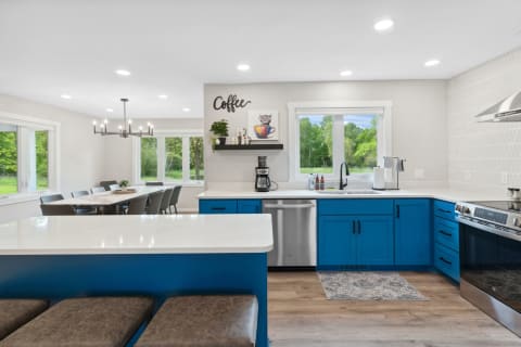 Modern kitchen featuring blue cabinets and a dining area with a large table.