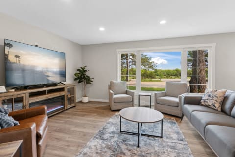 Modern living room with a large TV, comfortable seating, and a scenic outdoor view.