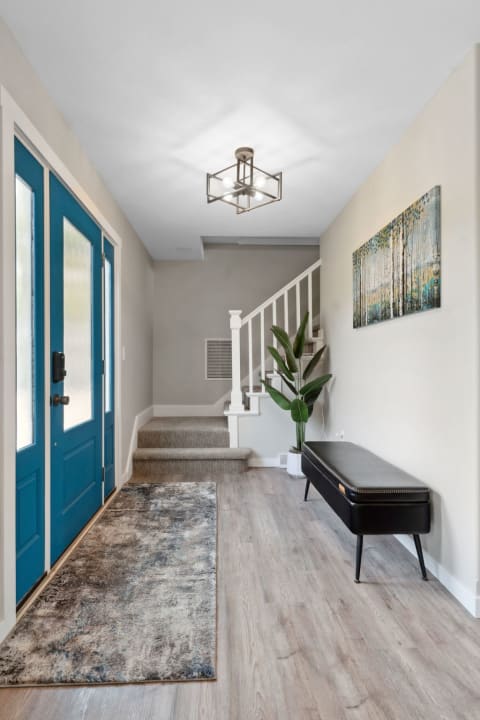 Bright and modern entryway with blue double doors and a staircase.