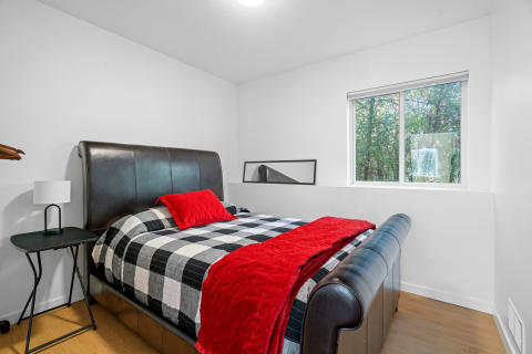 Modern bedroom featuring a leather bed with checkered bedding and a red throw blanket.