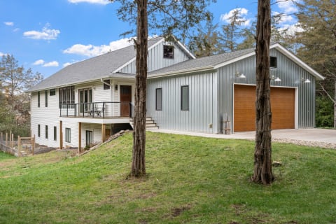 Two-story house featuring white siding and metallic cladding on a green lawn.