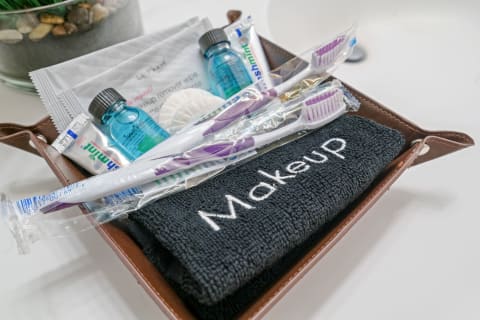 Personal care items in a brown tray including a towel, toothbrushes, toothpaste, and makeup remover essentials.