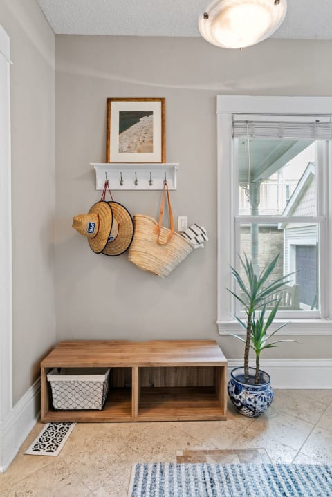 A cozy entryway featuring a shelf with hats, a wooden bench, and a plant.