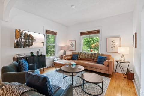 Stylish living room with leather sofa, wooden coffee tables, and large windows.