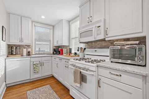 Bright modern kitchen featuring white cabinets and gray countertops.