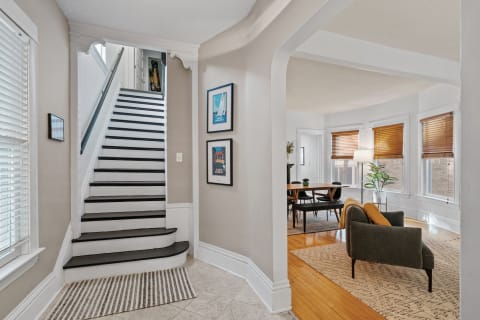 Bright entryway with a staircase leading upstairs and a cozy seating area in view.