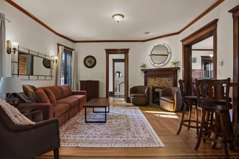 Interior of a cozy living room featuring rich wood details, comfortable seating, and a fireplace.